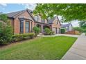 Well-maintained brick house boasting a lush green lawn, mature trees, and an attached two-car garage at 6477 Blue Water Dr, Buford, GA 30518