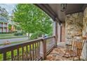 Inviting front porch adorned with stone accents, a cozy rocking chair, and a view of the neighborhood at 6477 Blue Water Dr, Buford, GA 30518