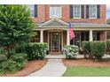 Close-up of a quaint front porch with brick columns and an American flag at 910 Ovalene Sw Ln, Marietta, GA 30064