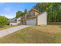 Side view of home featuring a two-car garage, and a well-maintained yard, set against a lush, green backdrop at 1450 Steam Engine Way, Conyers, GA 30013