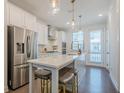 Modern kitchen with stainless steel appliances, white cabinetry, island with bar stools, and wood floors at 3693 Allegretto Cir, Atlanta, GA 30339