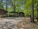View of the car port and a matching shed, nestled among mature trees, adding extra outdoor storage at 5216 Wheeler Dr, Loganville, GA 30052