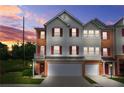 Attractive townhouse with a two-car garage, neutral siding, and brick accents against a colorful sunset at 5989 Turfway Park Ct, Sugar Hill, GA 30518