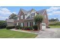 Elegant brick home featuring a well-maintained lawn, mature landscaping, attached garage, and inviting curb appeal at 1644 Beaver Creek Ln, Snellville, GA 30078
