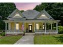 Charming yellow two-story home with inviting front porch, lush landscaping, and American flag at 161 N Barton St, Norcross, GA 30071