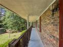 A cozy, covered side porch with brick wall and wood railing at 2000 Stone Mountain Lithonia Rd, Lithonia, GA 30058
