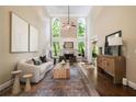 Bright living room with soaring ceilings, a fireplace, and large windows overlooking a green backyard at 3390 River Ferry Dr, Alpharetta, GA 30022