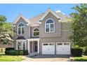 Charming two-story home with a two-car garage, arched windows, and neatly manicured landscaping at 4527 Village Springs Run, Dunwoody, GA 30338