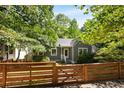 Exterior view of gray bungalow with a wooden fence and green trees surrounding the home at 1367 Ormewood Se Ave, Atlanta, GA 30316