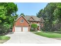 Lovely brick home with manicured lawn, mature trees, two-car garage, and long driveway at 140 Longwater Cv, Roswell, GA 30075