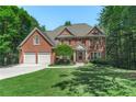 Beautiful brick home with a well-manicured lawn, a two car garage, and mature trees at 140 Longwater Cv, Roswell, GA 30075