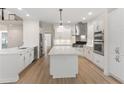 Bright kitchen features white cabinetry, stainless steel appliances, and center island with marble countertop at 140 Longwater Cv, Roswell, GA 30075