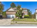 Lovely two-story brick home with lush green lawn and mature tree in the front yard at 1417 Sterlingbrooke Dr, Powder Springs, GA 30127