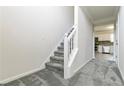 Carpeted staircase with white railing, leading to second floor and hallway with kitchen view at 2837 Lakewater Way, Snellville, GA 30039