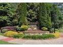 Beautifully landscaped community entrance sign with lush greenery and colorful flowers at 4171 Towncastle Ln, Buford, GA 30518