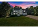 Two-story home at dusk featuring a covered front porch, attached garage, and large front lawn at 185 Waverly Walk, Douglasville, GA 30134