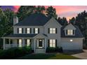 Two-story home at dusk featuring a covered front porch, attached garage, well-manicured lawn and shade trees at 185 Waverly Walk, Douglasville, GA 30134