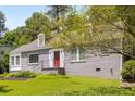Well-maintained grey brick home featuring dormer windows, a red front door and lush green lawn at 6596 Wright Ne Rd, Atlanta, GA 30328