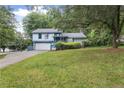 Charming blue two-story home with a well-maintained lawn and mature trees in the front yard at 9760 Loblolly Ln, Roswell, GA 30075