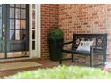 Inviting front porch featuring a bench, decor, and brickwork, next to the front door at 4905 Village Green Dr, Roswell, GA 30075