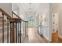 Bright foyer featuring hardwood floors, a staircase with iron railing, and elegant lighting fixtures at 5105 Deerlake Dr, Alpharetta, GA 30005