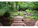 Beautiful landscaping in the backyard with wooden steps, a small waterfall, and lush greenery at 161 Highgrove Dr, Suwanee, GA 30024