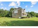 Expansive backyard featuring lush green lawn, mature trees, and the home's exterior with brick and light siding at 327 Awendaw Cir, Ellenwood, GA 30294