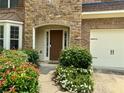 Close-up view of front entrance featuring stone facade, well-maintained landscaping, and a light-colored two car garage at 3389 Rosecliff Trce, Buford, GA 30519