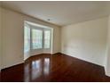 Sunlit living room with hardwood floors and a large bay window offering ample natural light at 3389 Rosecliff Trce, Buford, GA 30519