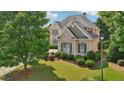Beautiful home exterior showcasing lush landscaping, mature trees, and well-maintained lawn at 2871 Trailing Ivy Way, Buford, GA 30519