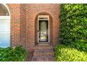 Close up of the front door with an arch, a brick facade, and lush green bushes on either side at 980 Windsor Place Cir, Grayson, GA 30017