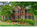 Traditional two-story brick home with black shutters and a manicured lawn and mature shade trees at 3642 Fowler Rdg, Douglasville, GA 30135