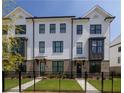 Beautiful townhome with brick accents, dark trim windows, a grassy yard, and a wrought iron fence around the property at 502 Healy Dr # 76, Cumming, GA 30040