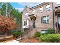 Brick townhome featuring a welcoming entrance with stairs, complemented by lush greenery and mature trees at 3786 Alstead Manor Way, Suwanee, GA 30024