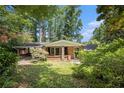 Charming single-story brick home featuring an attached carport and lush, mature landscaping under blue sky at 2595 Woodhill Cir, Atlanta, GA 30344