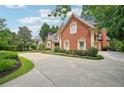 Long driveway leading to a red brick home surrounded by lush landscaping at 8250 Saint Marlo Fairway Dr, Duluth, GA 30097
