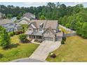 Aerial view of a two-story stone house with a well-manicured lawn, landscaping, and three-car garage at 776 Amos Ln, Kennesaw, GA 30152