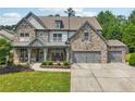 Stately two-story home with a stone facade, covered porch, three-car garage and lush landscaping at 776 Amos Ln, Kennesaw, GA 30152