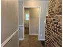 Hallway featuring neutral walls, an exposed brick accent wall, and a glimpse of an exterior door at the end at 172 Camp Sunrise Nw Rd, Cartersville, GA 30121