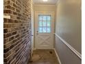 Hallway featuring neutral walls, an exposed brick accent wall, and an exterior door with a window at 172 Camp Sunrise Nw Rd, Cartersville, GA 30121