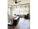 Bright main bedroom with a ceiling fan, large windows with sheer curtains, and cozy seating area at 6128 Lanier Harbor Lndg, Buford, GA 30518