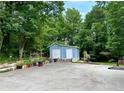 Charming light-blue shed with double doors and a variety of potted plants and garden features at 7326 Leland Ln, Jonesboro, GA 30236