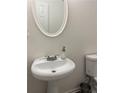 Charming half-bathroom featuring a pedestal sink, toilet, and oval mirror at 1263 Brookstone Rd, Atlanta, GA 30349