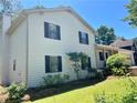 Side view of a two-story home with a chimney, black shutters, and lush landscaping at 1028 Gate Post Ln, Lawrenceville, GA 30044