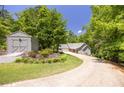 Beautiful home with long driveway, gray exterior and spacious shed surrounded by mature trees and flowers at 390 Rock Springs Pass, Dallas, GA 30157