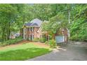 Elegant brick home featuring an attached garage, lush landscaping, and a pristine lawn at 8470 Valemont Dr, Atlanta, GA 30350