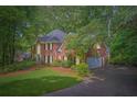 Elegant brick home featuring an attached garage, lush landscaping, and a pristine lawn at 8470 Valemont Dr, Atlanta, GA 30350