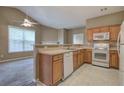 Functional kitchen with wooden cabinetry, view to living area, and standard white appliances at 580 Camry Cir, Dallas, GA 30157