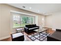 Bright living room featuring hardwood floors, large window, and a comfortable black leather sofa at 2742 Alpine Rd, Atlanta, GA 30305