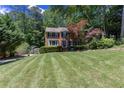 Well-maintained brick home with lush green lawn, mature trees, and a basketball hoop in the driveway at 2122 Rockland Ct, Marietta, GA 30062